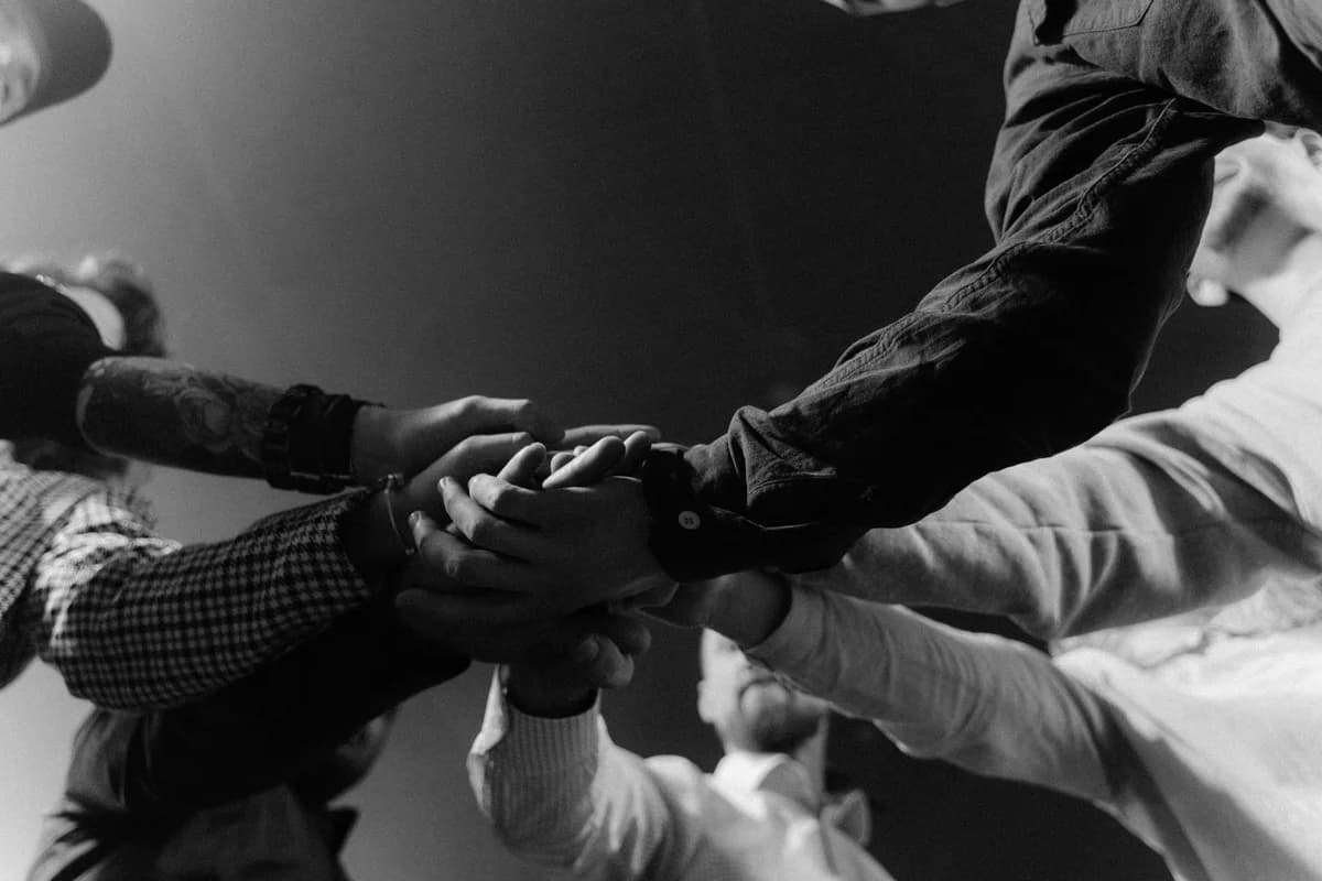 Several people stack their hands together in a teamwork gesture.