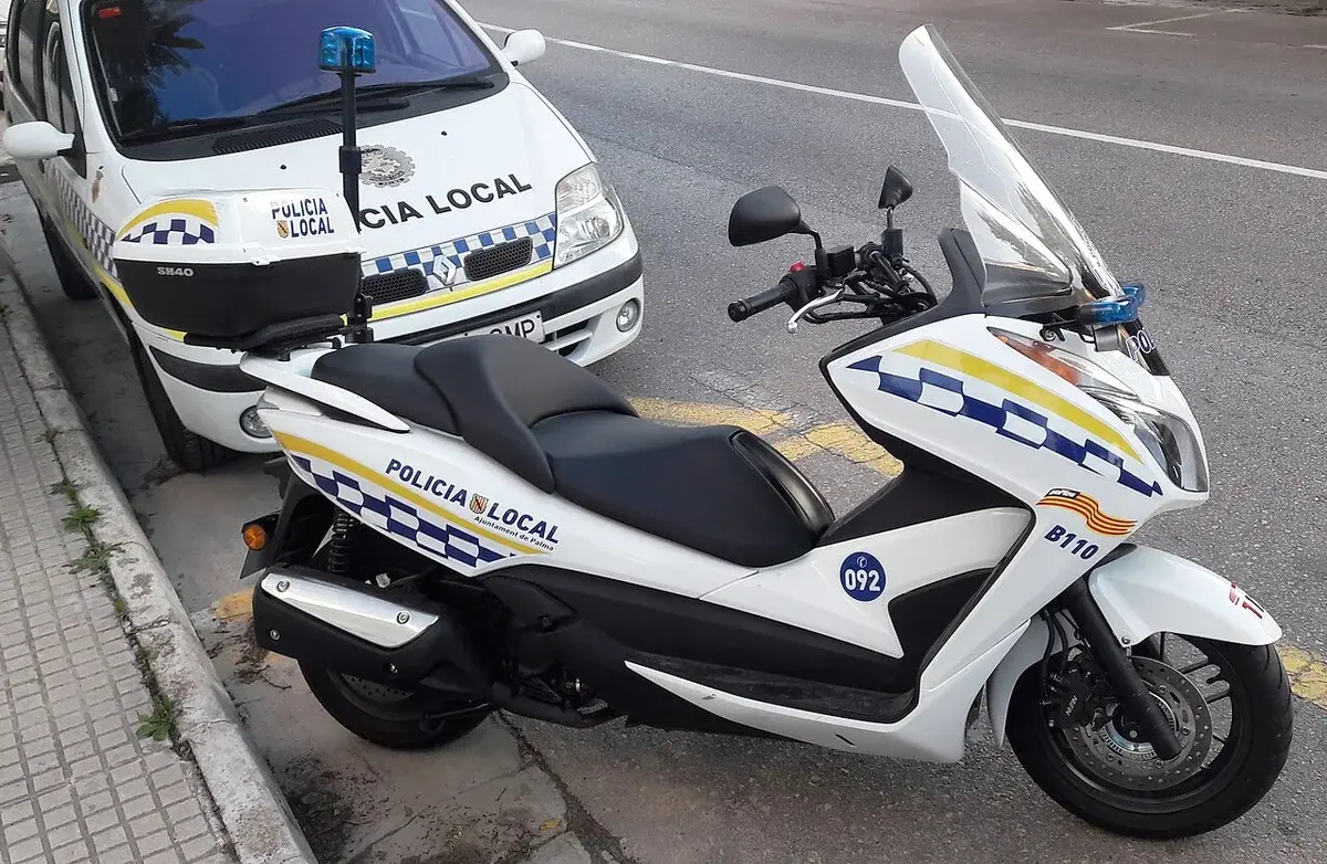 A local police motorcycle and car parked on a street.