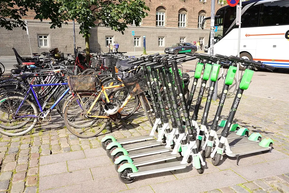 Parked electric scooters and bicycles on a Copenhagen street.