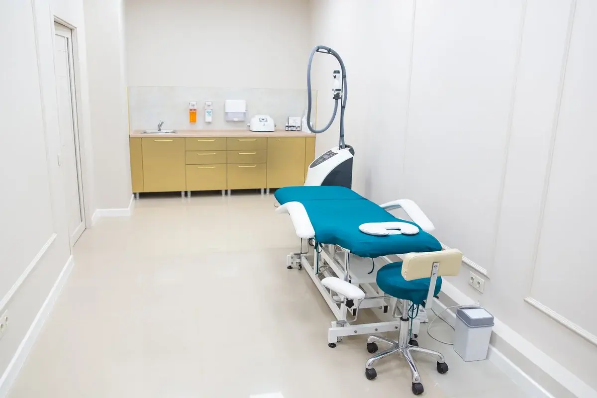 An empty modern medical examination room with a treatment chair and equipment.