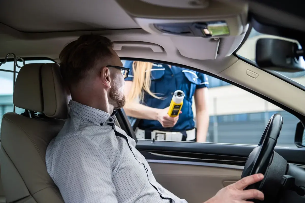 Police officer performing a breathalyzer test on driver at roadside