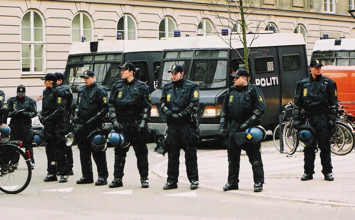 Danish police officers in riot gear standing in front of police vans in Copenhagen