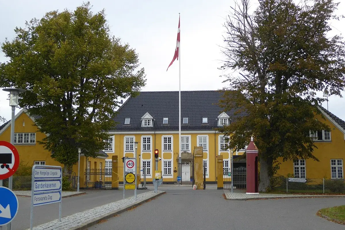 Yellow barracks building with a Danish flag and entrance signs
