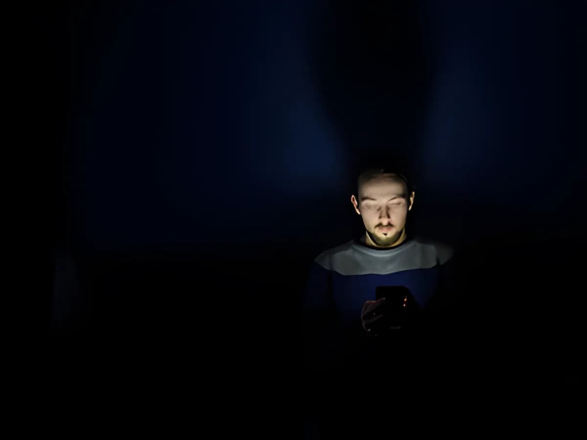 Man looking at smartphone in dark room