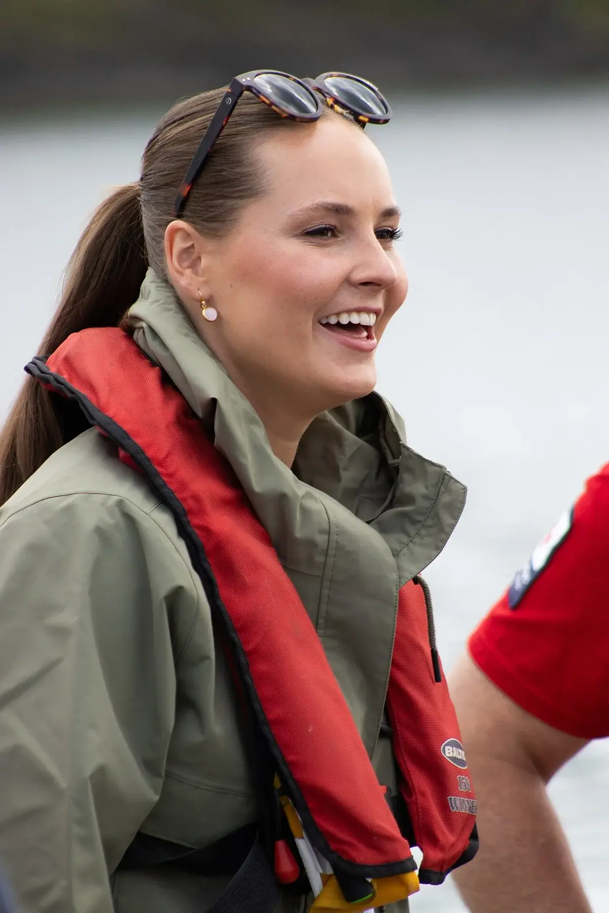 Princess Ingrid Alexandra smiling in a life vest at a waterfront event.