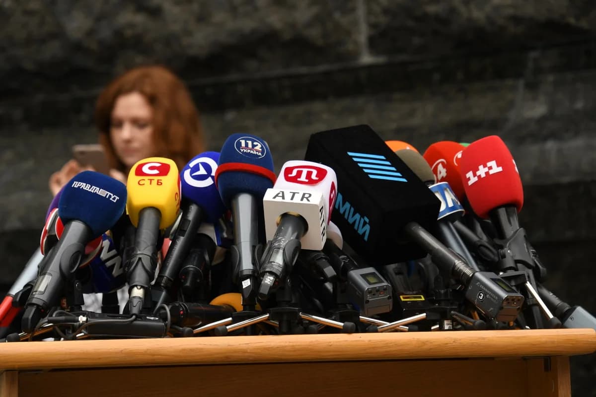 Many branded microphones are set up on a podium for a press conference.
