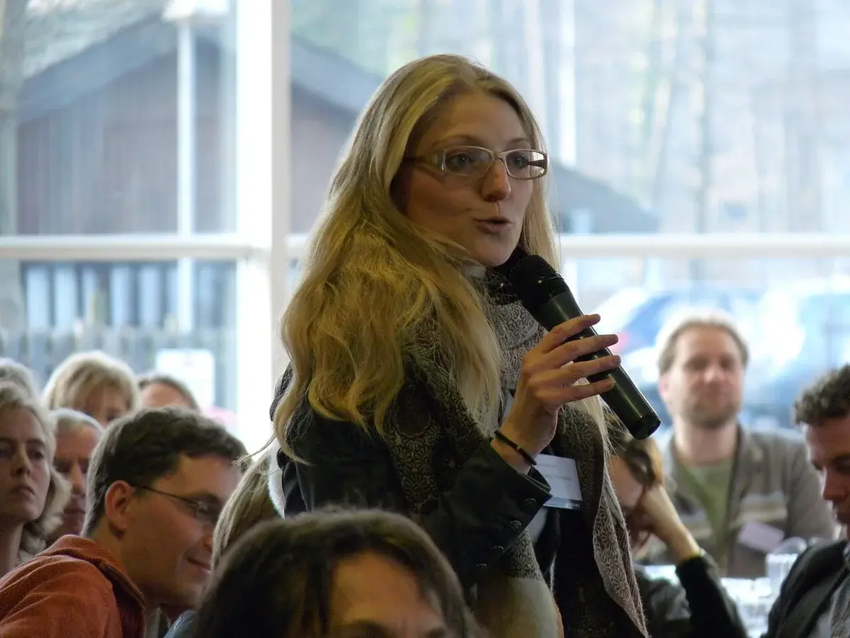 Zenia Stampe speaking into a microphone at an indoor event.