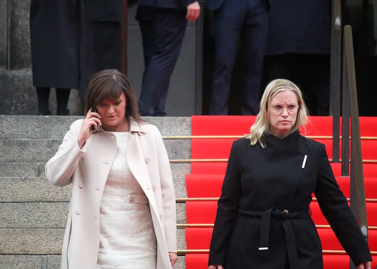 Two women standing outside Christiansborg Palace, one on a phone, after the opening of the Danish parliament.