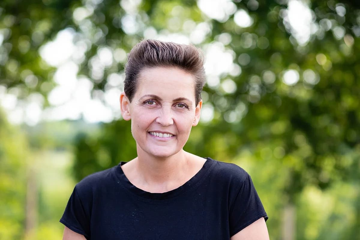 Portrait of Pia Olsen Dyhr standing outdoors against a blurred green background.