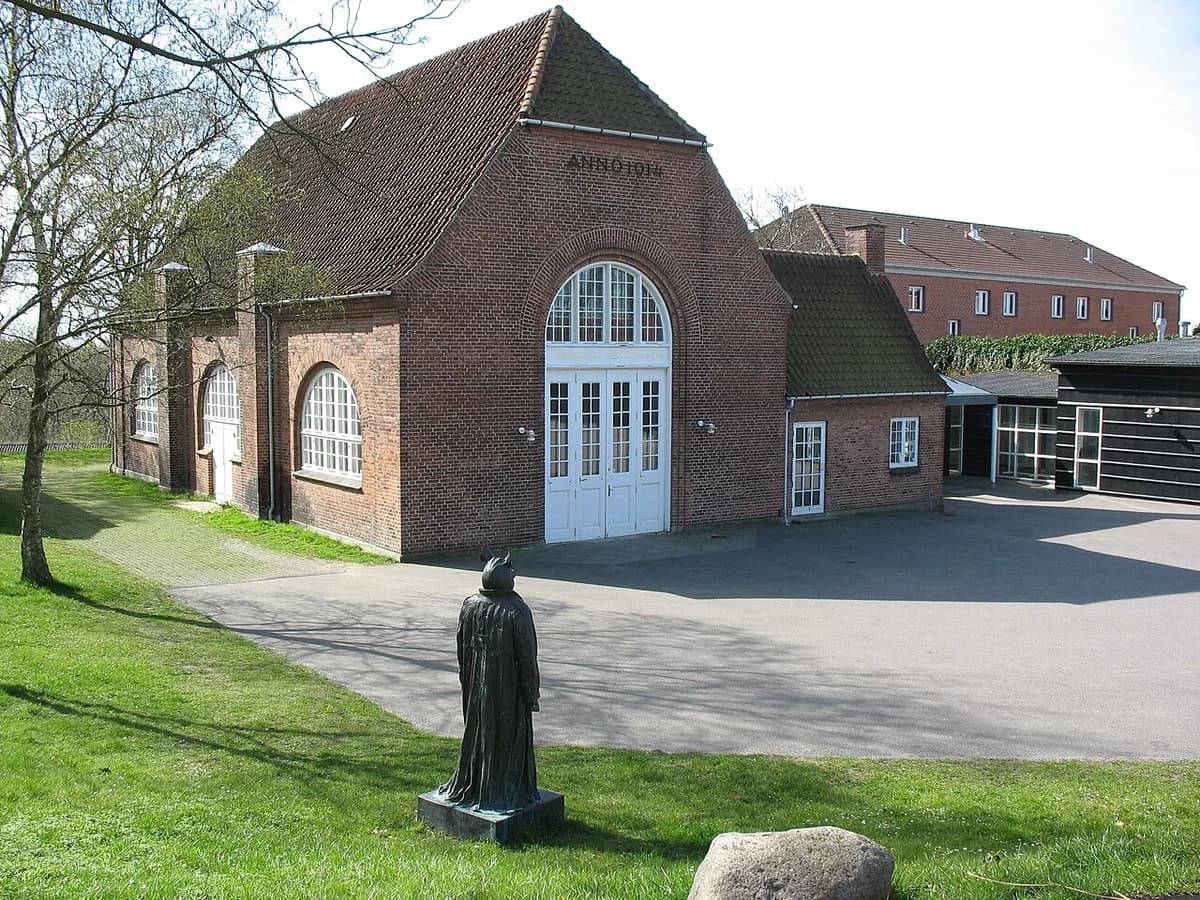 Brick cultural center building with arched windows and a statue on the lawn.