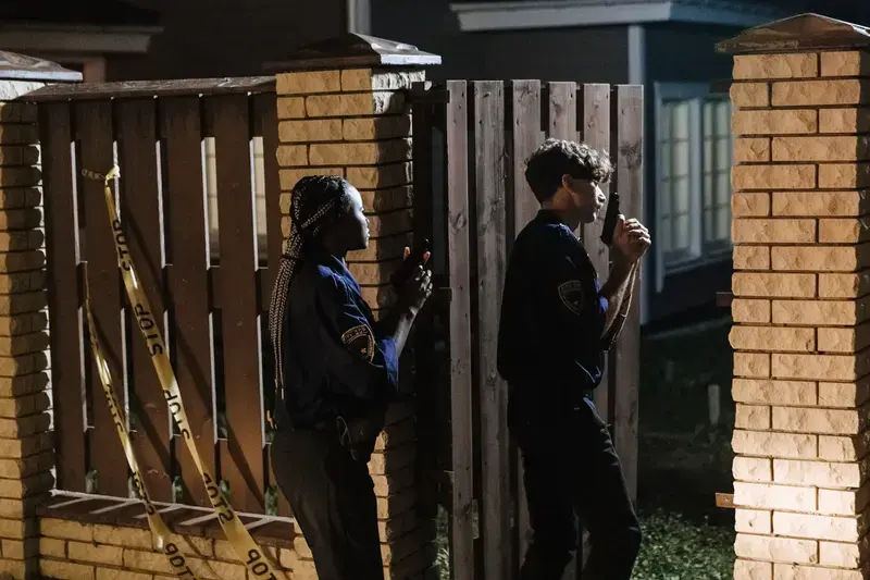 Two police officers entering a house at night with police tape around