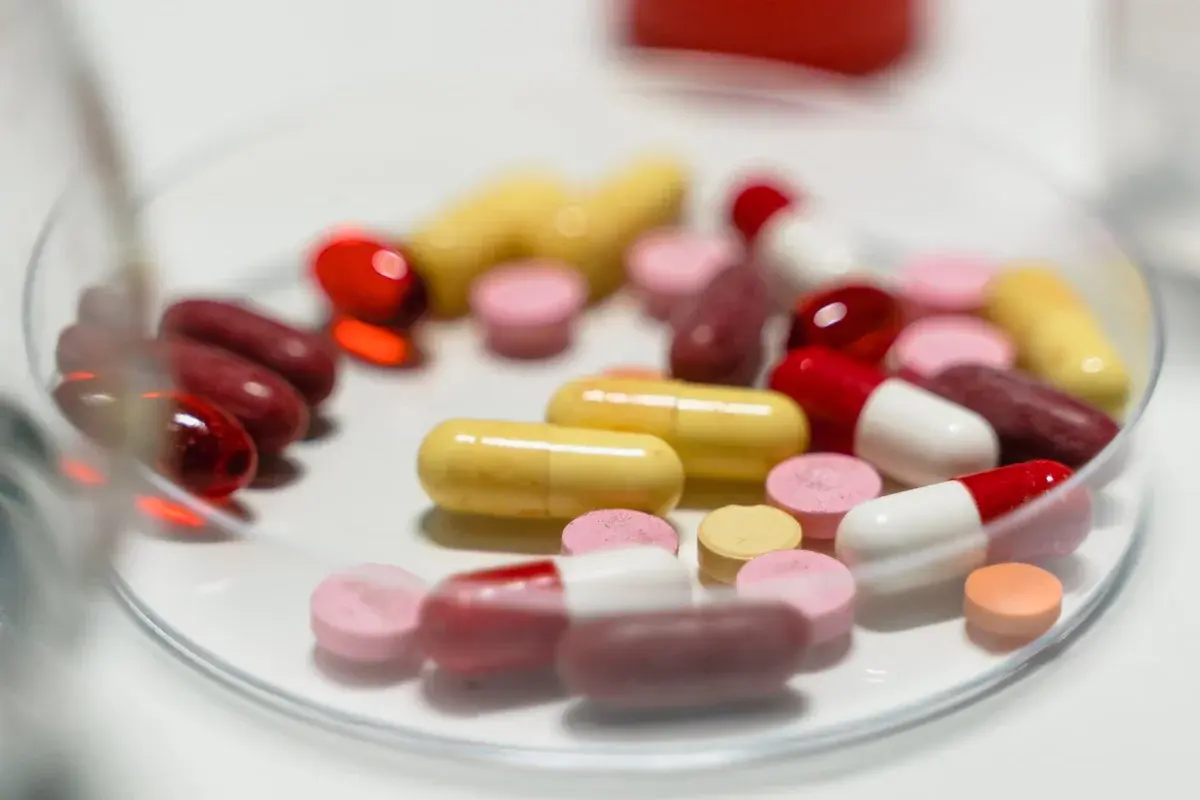 A petri dish filled with assorted colorful pills and capsules.