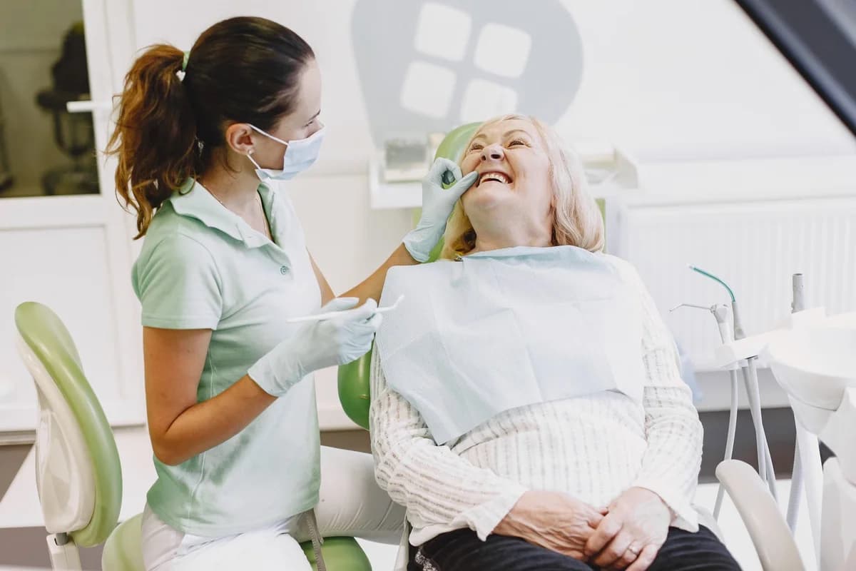 A female dentist examines an elderly woman in a dental chair.
