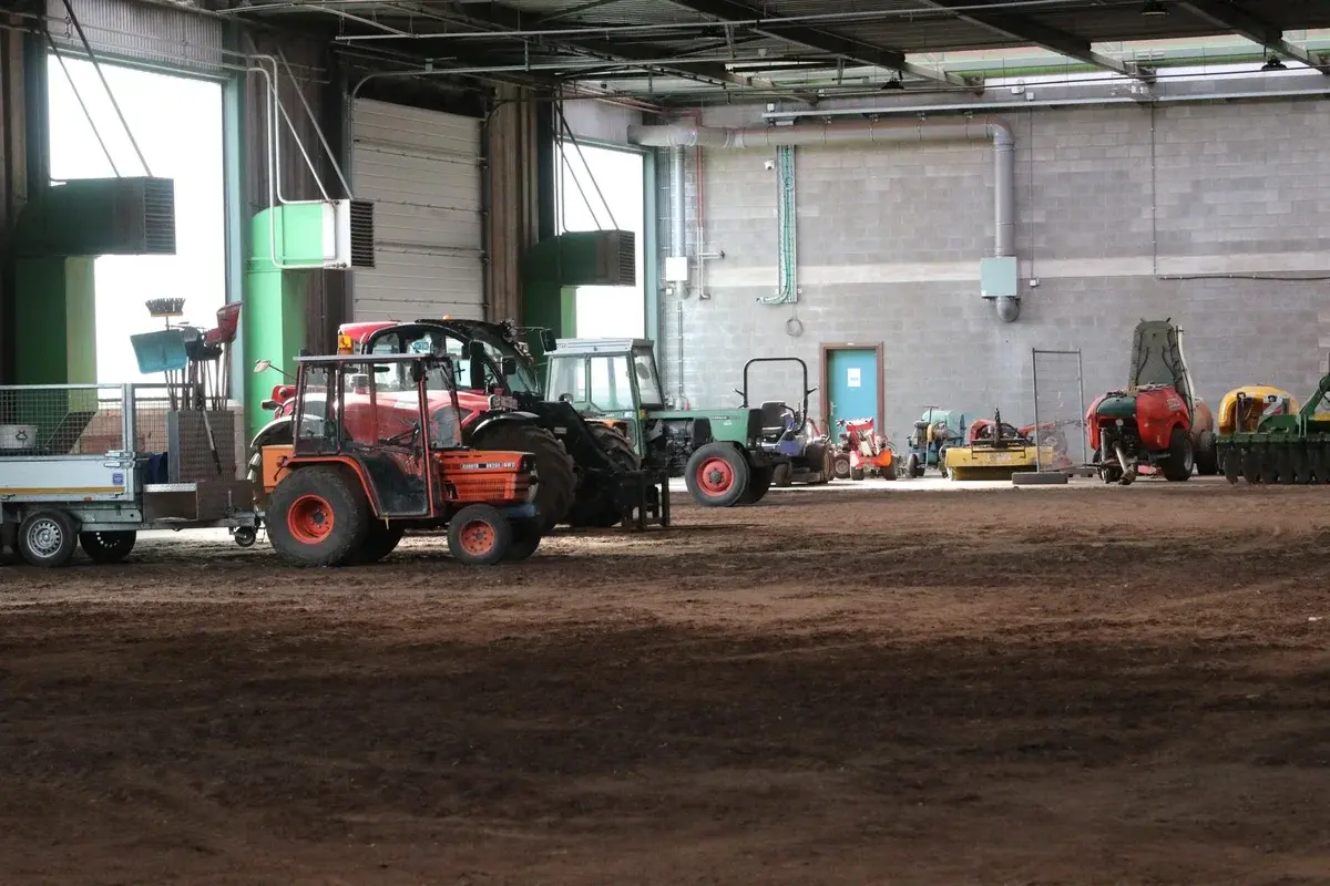Tractors and farm equipment stored inside a large indoor hall.