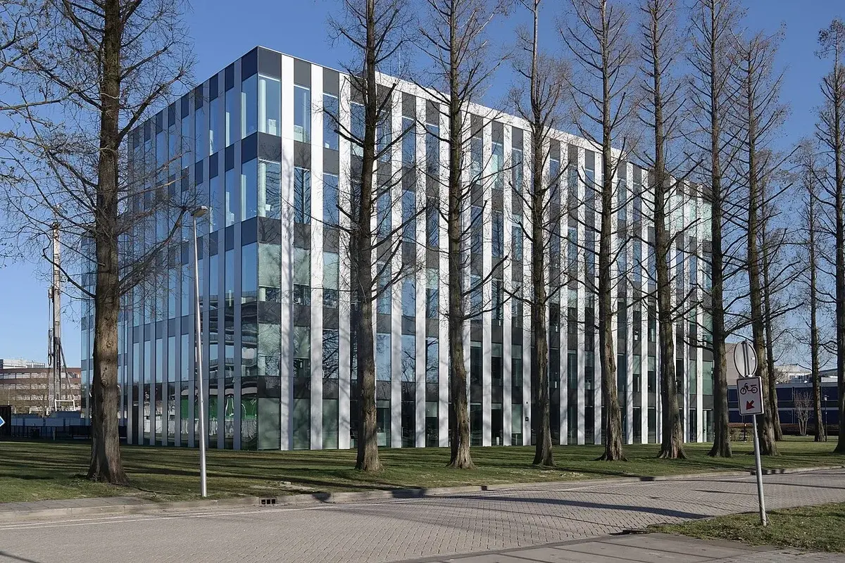 Modern glass office building behind leafless trees at Utrecht Science Park.