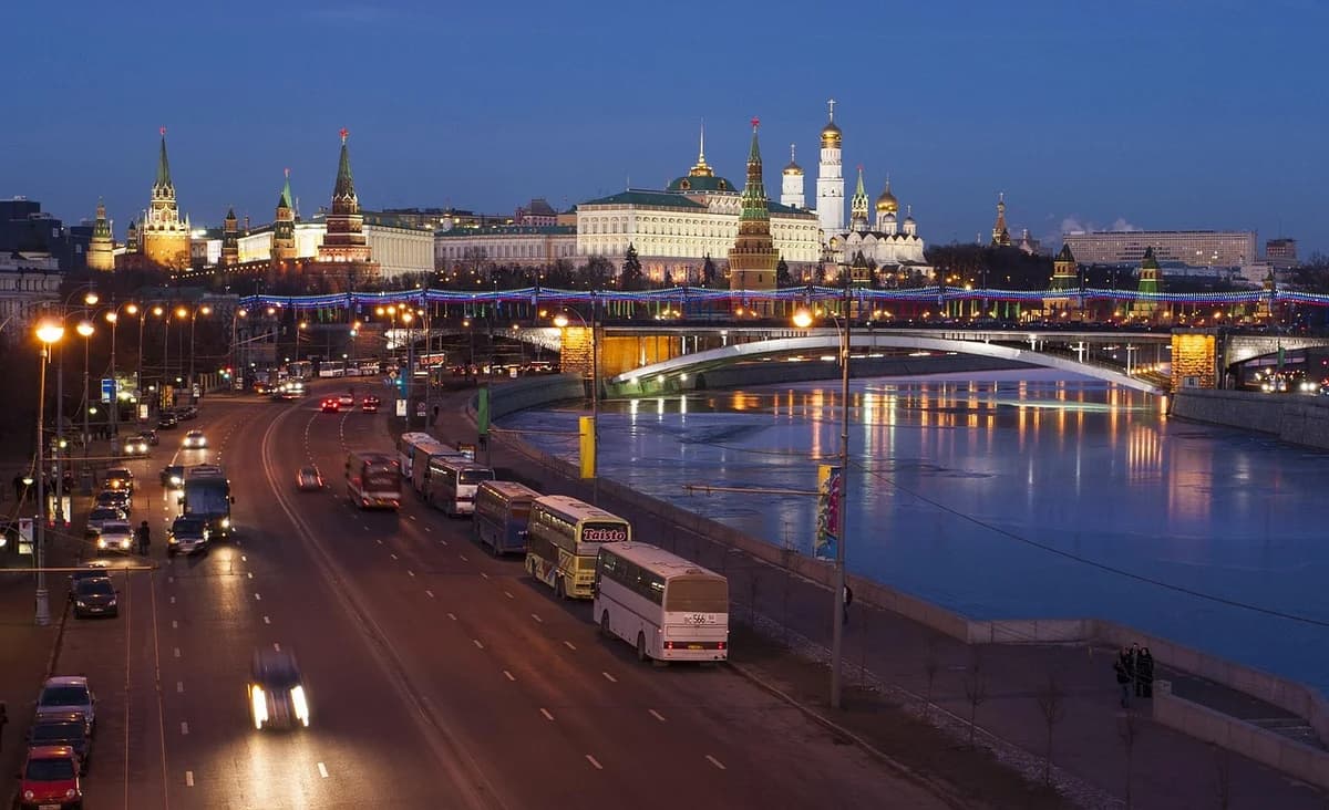 Night view of the Kremlin and Moscow River with illuminated buildings and a bridge.