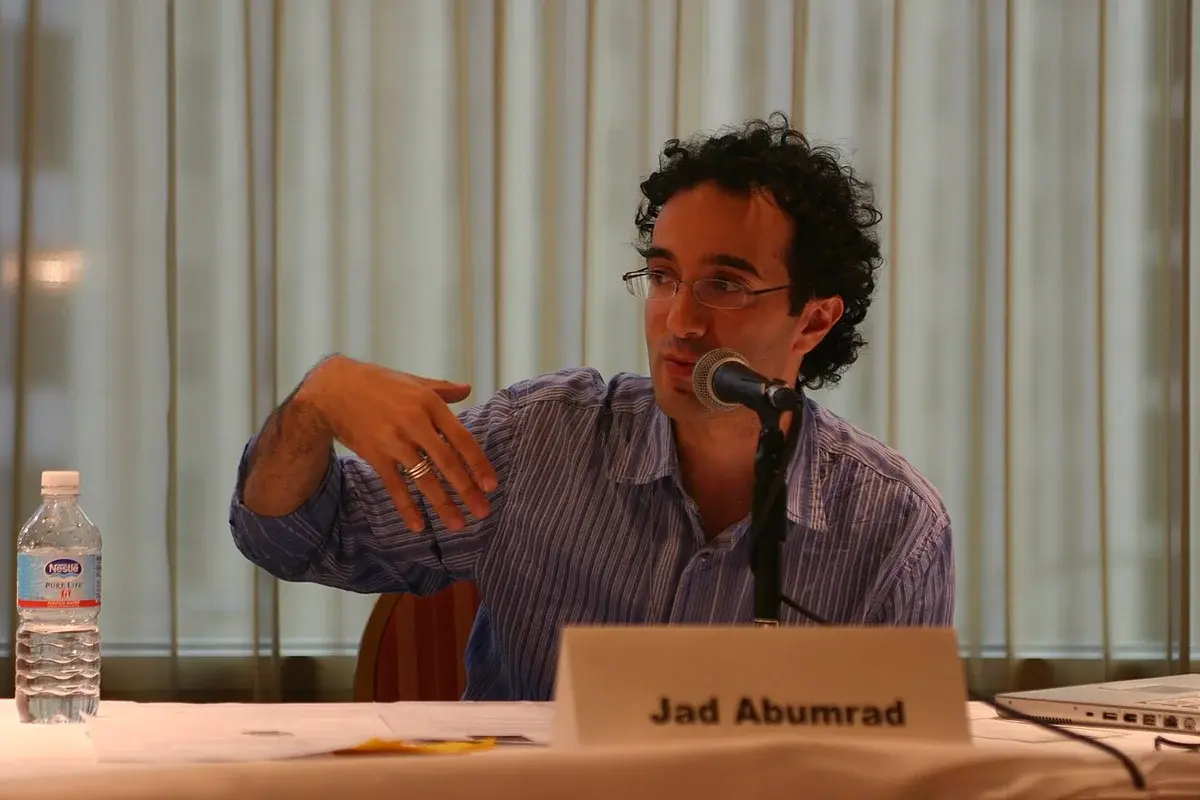 Jad Abumrad speaking into a microphone at a table.