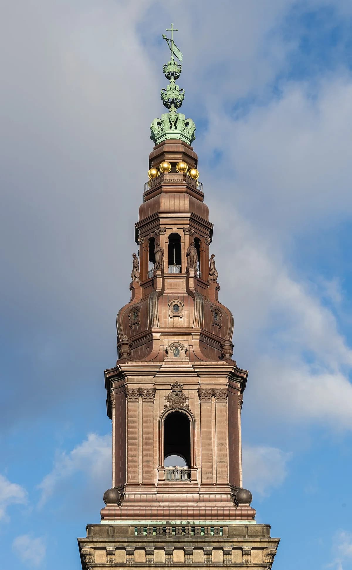 The ornate tower spire of Christiansborg Palace against a blue sky.