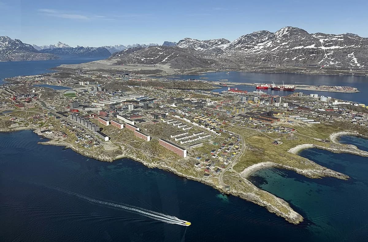 Aerial view of downtown Nuuk on the coast with mountains in the background.