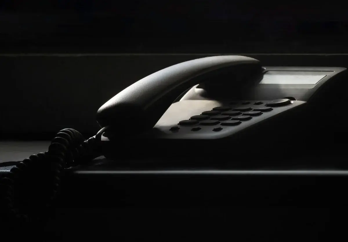 A vintage landline phone in dramatic shadow.