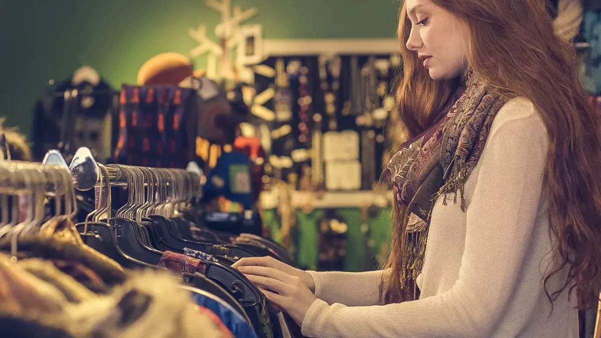 A young woman browsing clothes in a vintage-style shop.