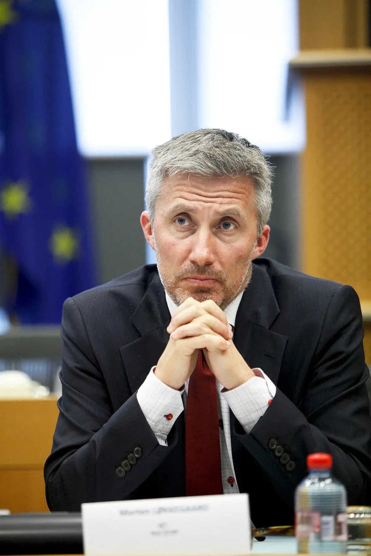 A Danish politician seated at a table with his hands clasped.