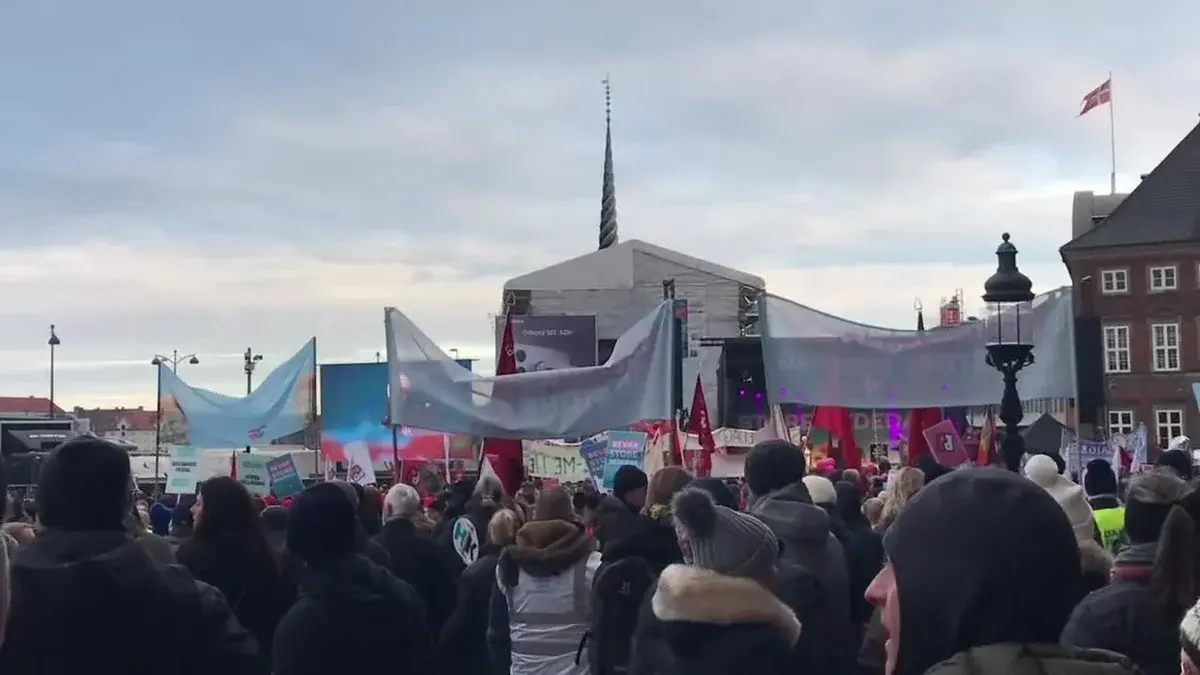 Crowd of protesters with banners gathered in Copenhagen.