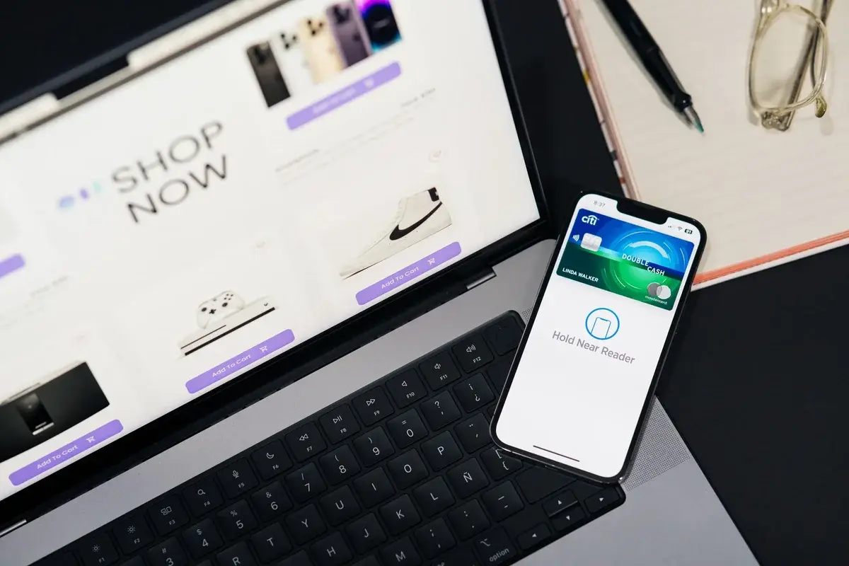 Laptop showing an online shopping site next to a smartphone with a mobile payment app.