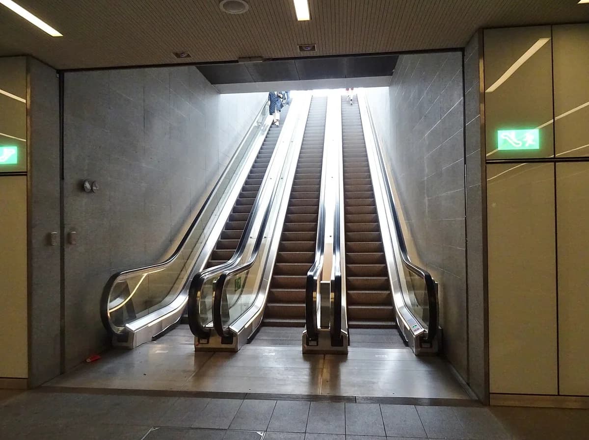 Three escalators inside an underground metro station leading up to street level.