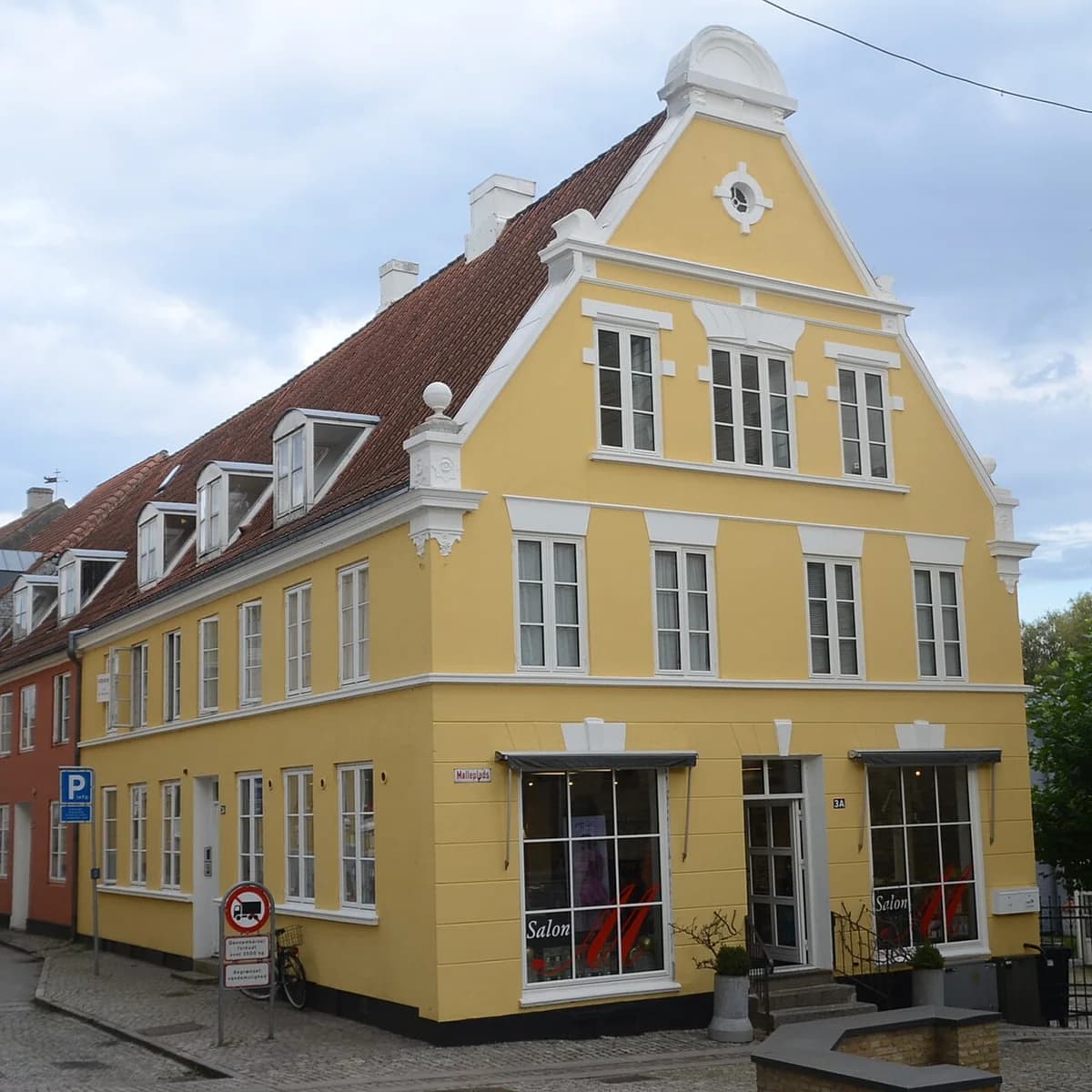 A yellow historic town house on a street corner in Haderslev.