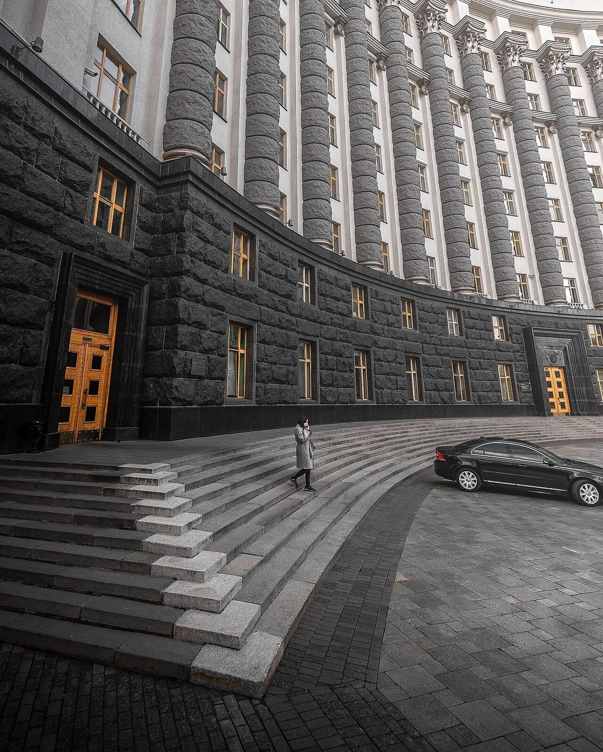 Exterior of a large government building in Kyiv with curved steps and a parked car.