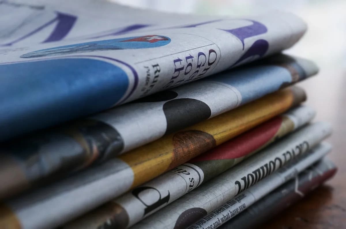 Close-up of folded newspapers stacked on a wooden surface.